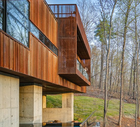 View of Pool and Spa with Vanishing Edge and Corten Rusted Steel Perforated Screens and Ribbed Metal Siding at Modern Bridge House Spanning Ravine on Concrete Piers by Best Charlottesville Architects HEDS Designed by Allison Ewing.