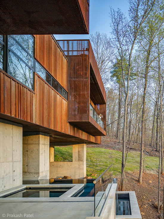 View of Pool and Spa with Vanishing Edge and Corten Rusted Steel Perforated Screens and Ribbed Metal Siding at Modern Bridge House Spanning Ravine on Concrete Piers by Best Charlottesville Architects HEDS Designed by Allison Ewing.