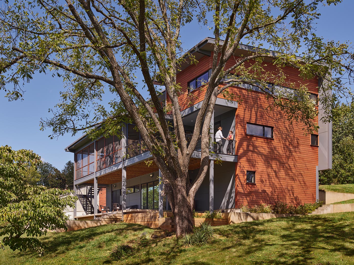 Modern House in Charlottesville with Orange Wood Siding, Screen Porch at Second Floor, Deep Overhangs and Painted Steel Metal Stair Designed by Charlottesville, Virginia Green Architect HEDS and Chris Hays.