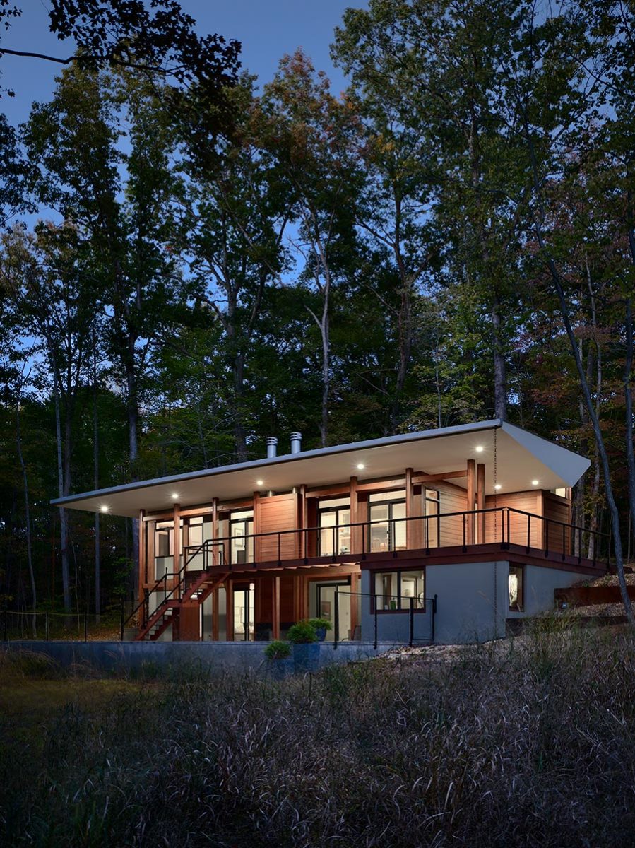 Night View of Modern Home with Large Roof Overhangs, Wood Shiplap Siding and Wood Deck Designed by Charlottesville Architect.