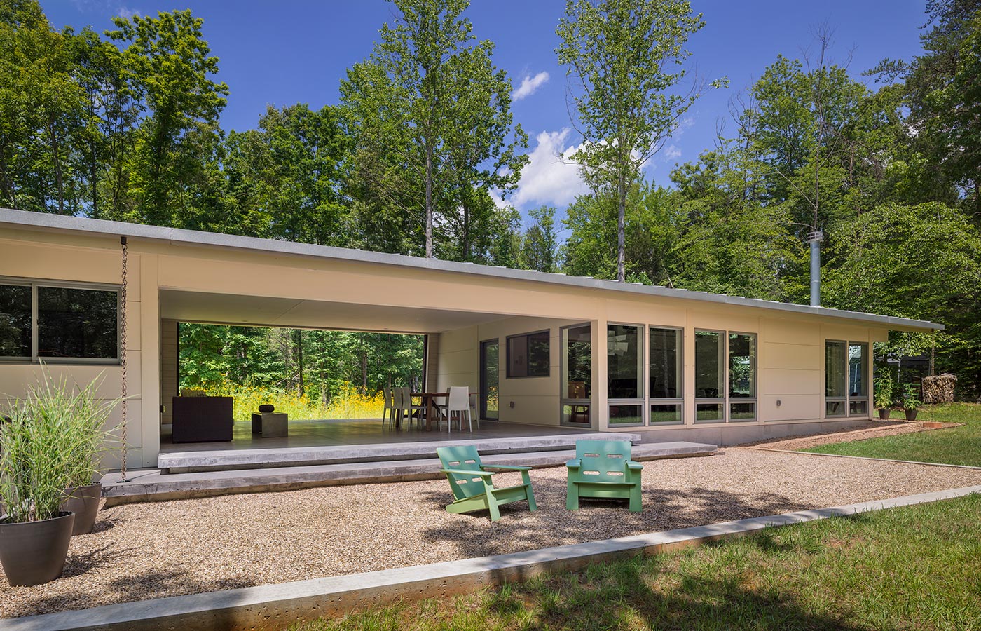 Richmond Road Modern Dogtrot House with Open Covered Porch Between Living Area and Bedrooms with Hardipanel Siding and Wildflower Meadow beyond by Chris Hays, Charlottesville-based Architect of HEDS.